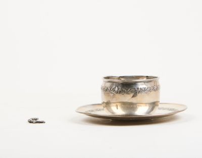 a silver cup and saucer sitting on a saucer