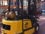 a yellow fork truck parked in a warehouse with barrels on the back of it