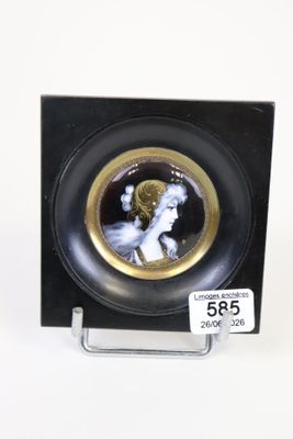 une photo d'une assiette noire et dorée sur laquelle figure le portrait d'une femme