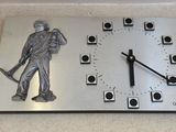 a metal clock with a statue of a man holding a baseball bat