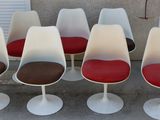 six chaises « Tulip » avec des coussins rouges devant une porte de garage