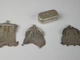 trois bourses en argent et une boîte en argent posées sur une surface blanche