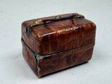 a small brown leather box with a handle on it