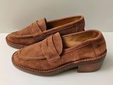 un gros plan sur une paire de chaussures marron posées sur une surface blanche