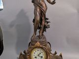 a statue of a woman holding a clock on a table
