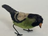 un petit oiseau en peluche posé sur une surface blanche