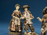 three figurines of people dressed in traditional clothing on a blue background
