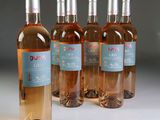 four bottles of pink wine are lined up on a table