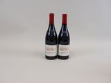 two bottles of red wine sitting next to each other on a white surface