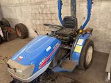 un tracteur bleu garé dans un garage, près d'un mur