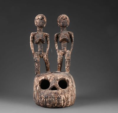 deux figurines en bois sculptées, dont l'une tient un crâne et l'autre un être humain