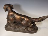 bronze statue of a dog sitting on a rock on a white surface