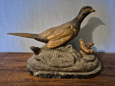statue représentant un oiseau et un canard posés sur un rocher, posée sur une table