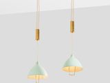 a pair of light green and gold pendant lights hanging from a ceiling