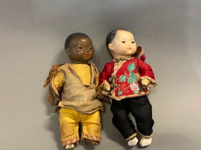 two dolls sitting next to each other on a table