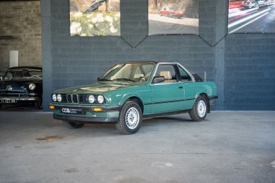 une voiture verte garée dans un garage à côté d'une voiture noire