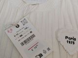 a white sweater with a heart patch on it