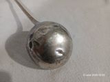 une cuillère sur laquelle est fixée une bille métallique, posée sur une table