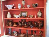 une bibliothèque rouge sur laquelle sont disposés de nombreux vases de toutes sortes