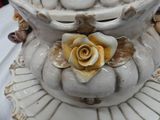 a white vase with a yellow rose on top of it