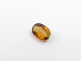 a yellow sapphire stone on a white surface