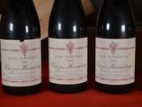 four bottles of wine are lined up on a red table