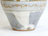 a close up of a blue and white vase on a white surface