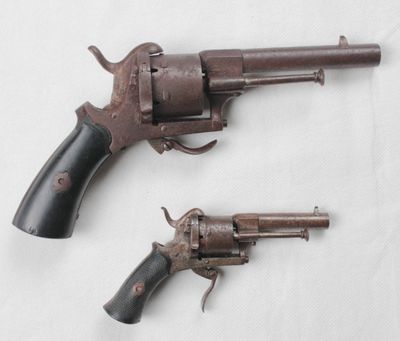 une paire de vieux revolvers posés l'un à côté de l'autre sur une surface blanche