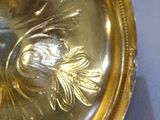 a gold plate with a bird on it on a table