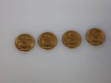four gold sovereigns are shown in a row on a white surface