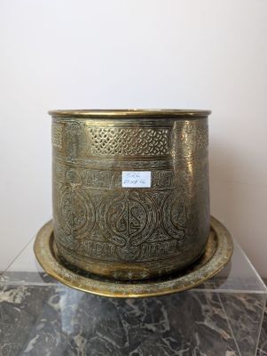 un vase en or posé sur une table en marbre, sur lequel est apposée une étiquette