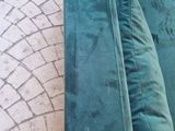 a green couch with pillows on it sitting on a brick floor