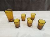 yellow glass shot glasses sitting on top of a table next to each other
