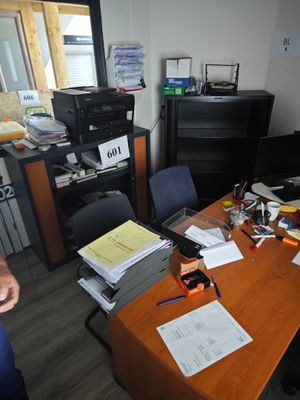 un homme assis à un bureau, entouré d'une pile de papiers