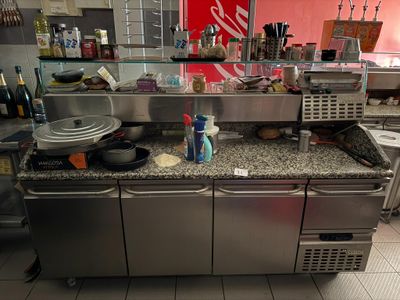 un plan de travail en acier inoxydable dans la cuisine d'un restaurant, sur lequel sont posés de nombreux plats