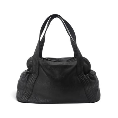 Le grand sac à main noir est posé sur une surface blanche.