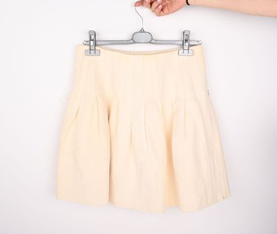 short plissé beige sur un cintre devant un mur blanc