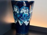 a blue vase sitting on top of a shelf next to a wall