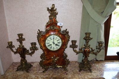 une horloge posée sur une table, avec des bougies et un bougeoir