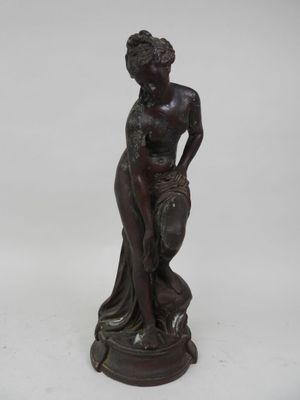 une statue antique en bronze représentant une femme tenant un panier