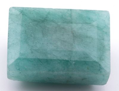 un gros plan d'une pierre verte sur une surface blanche