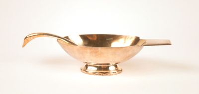 a silver bowl with a spoon in it on a white surface