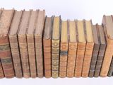 several old books stacked on top of each other on a white surface