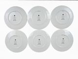 six white plates with black writing on them sitting on a white surface
