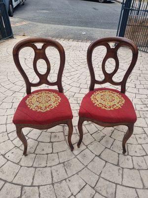 pair of antique chairs with red upholstered seats on a brick patio