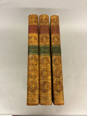 trois vieux livres posés l'un sur l'autre sur une table