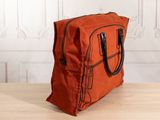 an orange bag sitting on top of a wooden table next to a white wall
