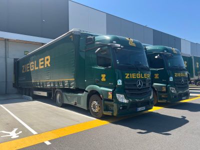 several green trucks parked in a parking lot next to a building