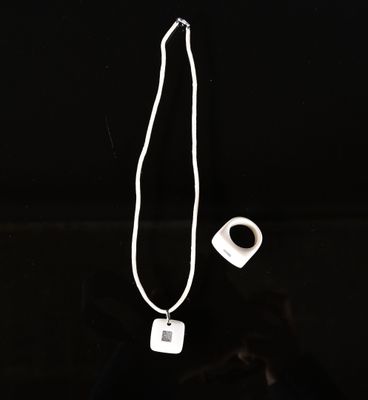 un collier blanc auquel est accroché un objet de forme carrée