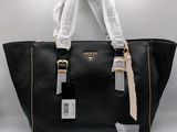 black leather tote bag with gold hardware and white ribbon